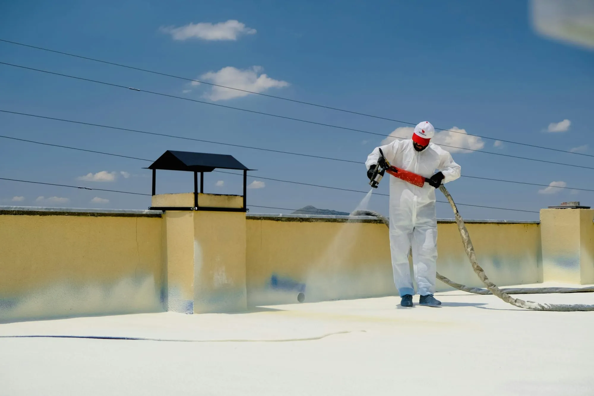 A waterproofing technician spray-applying a seamless membrane across a flat terrace roof
